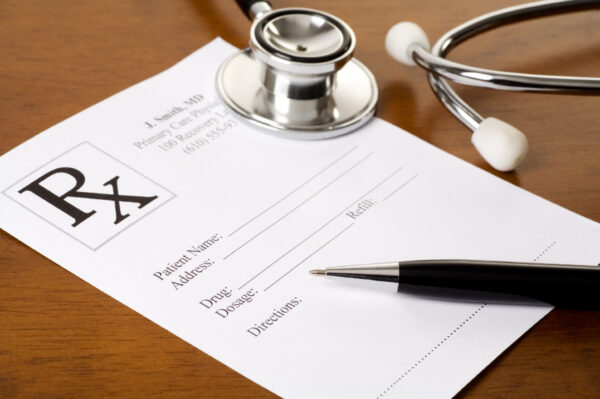 A prescription form, pen, and stethoscope on a doctor's desk.