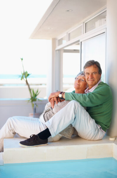 Couple Sitting Together By The Swimming Pool On Their Vacation