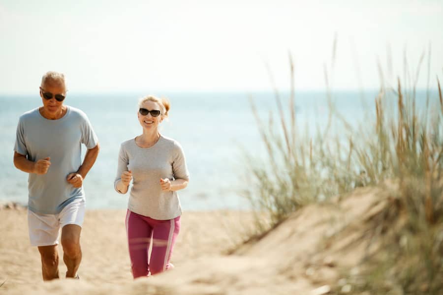 Seniors Jogging on beach with ocean in the background